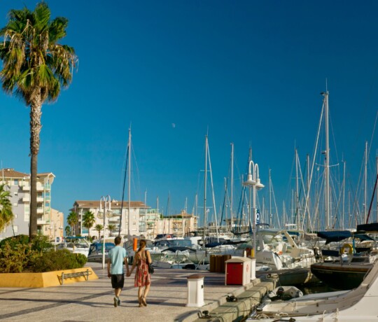 Port Frejus was created in 1982. people cycling trought the harbor along terraces of restaurants